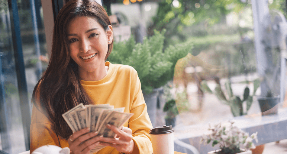 woman in yellow sweater holding money